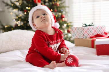Evde, Noel Baba şapkası takıp yatakta takılan şirin bir bebek. Noel sezonu