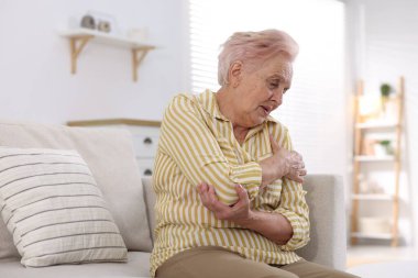 Evde omuz ağrısı çeken yaşlı bir kadın. Romatizma belirtileri