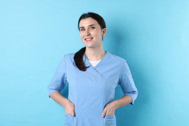 Açık mavi arka planda tıp üniformalı bir doktor.