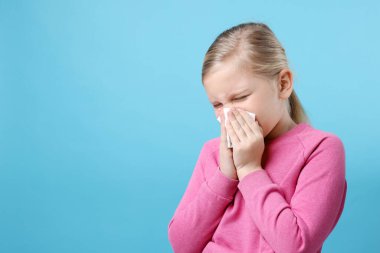 Açık mavi arka planda burnu akan küçük bir kız, mesaj için yer var. Soğuk Semptom