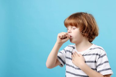 Küçük çocuk açık mavi arka planda öksürüyor, mesaj için yer var. Soğuk Semptom