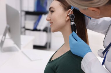 Duyma testi. Doktor, klinikte hastaların kulaklarını otoskop ve pamuklu bezle muayene ediyor. Metin için boşluk