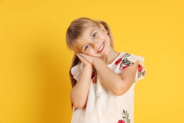 Sarı arka planda gülümseyen küçük kız portresi