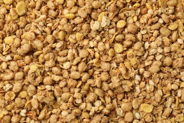 Arka planda yulaf taneleri olan lezzetli granola, üst görünüm.