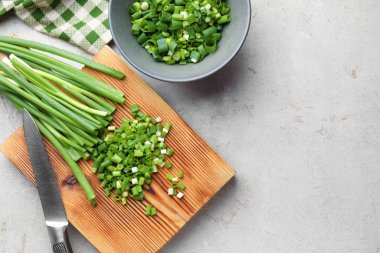 Açık gri masada yeşil soğan ve bıçak kes, düz yat. Metin için boşluk