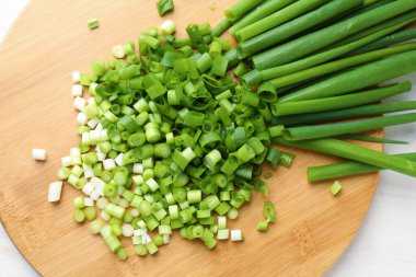 Açık ahşap masada taze yeşil soğan kes.