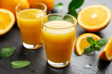 Taze portakal suyu ve siyah masada meyveler, yakın plan.