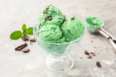 Çikolata parçalı lezzetli dondurma ve gri desenli masaya kepçe, yakın plan.