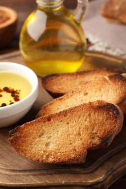 Izgara ekmek dilimleri, zeytinyağı ve baharatlar ahşap masada, yakın plan.