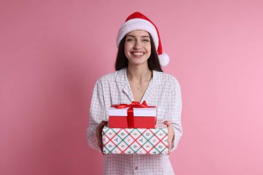 Pembe arka planda Noel Baba şapkalı mutlu kadın.