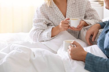 Evdeki sıcak içeceklerin tadını çıkaran sevimli çift, yakın plan.