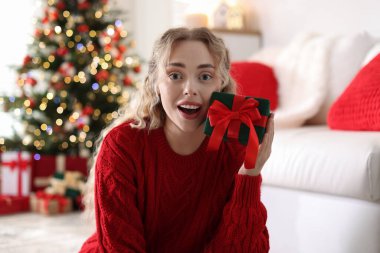 Evde bulanık ışıklara karşı Noel hediyesi giymiş mutlu kadın portresi.