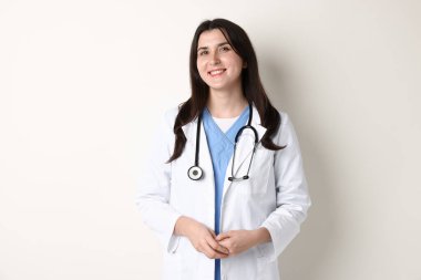 Doktor üniformalı, steteskoplu, beyaz arka planda.