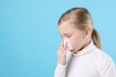Açık mavi arka planda burnu akan küçük bir kız, mesaj için yer var. Soğuk Semptom