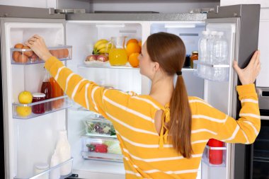 Mutfaktaki buzdolabından yumurta alan kadın.