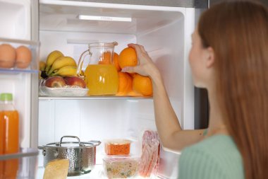 Mutfakta portakalı buzdolabından çıkaran kadın, yakın plan.
