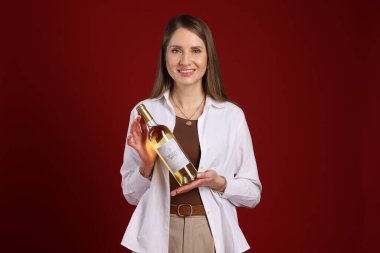 Kırmızı arka planda şarap şişesi olan profesyonel şarap garsonu.