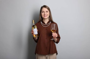 Açık gri arka planda cam ve bir şişe beyaz şarap ile profesyonel şarap garsonu.