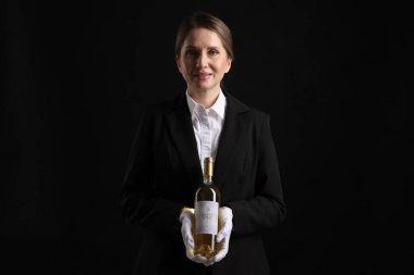 Siyah arka planda beyaz şarap şişesi olan profesyonel şarap garsonu.