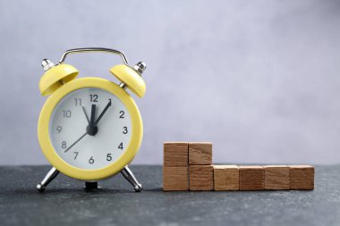 Alarm saati ve siyah masanın üzerindeki boş tahta küpler.