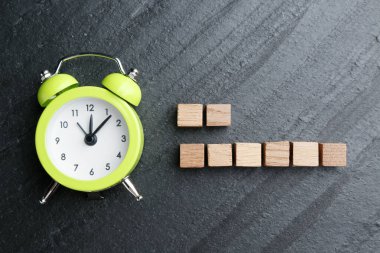 Çalar saat ve boş tahta küpler siyah masanın üzerinde, düz yatıyordu