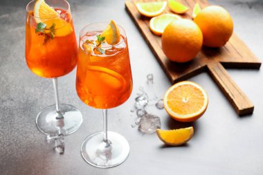 Gri masada serinletici spritzer kokteyli ve portakallar.