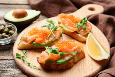 Havyar, somon, avokado ve mikroyeşillik ile nefis bruschetalar ahşap masada servis edilir.