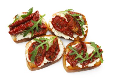 Krem peynirli lezzetli bruschettalar, güneşte kurutulmuş domatesler ve beyaza izole edilmiş roka.