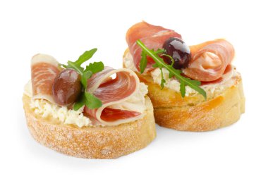Krem peynirli nefis bruschettalar, prosciutto, marine edilmiş siyah zeytin ve beyaz üzerine izole edilmiş roka.