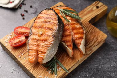 Lezzetli ızgara somon bifteği, domatesli ve biberiyeli, yakın plan.