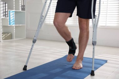 İçeride koltuk değneği kullanan yaralı bir adam, yakın plan.