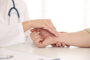 Doktor masadaki parmaklarıyla adamın nabzını kontrol ediyor.