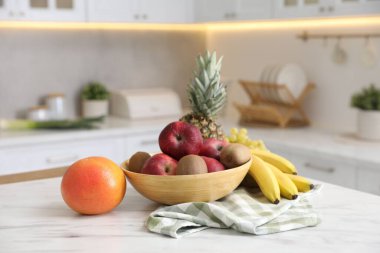 Mutfaktaki beyaz mermer masada farklı taze meyveler.