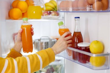 Mutfaktaki buzdolabından meyve suyu alan kadın, yakın plan.