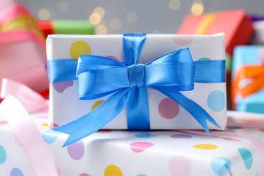 Gri arka planda güzel paketlenmiş hediyeler, bulanık ışıklar, yakın plan. Bokeh etkisi