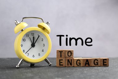 Harekete geçme zamanı. Gri masada çalar saat ve tahta küpler.