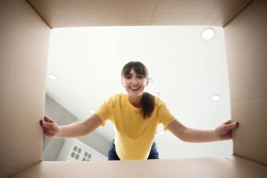 Kadın odada tavana bakan karton kutuya bakıyor, içeriden görüyor