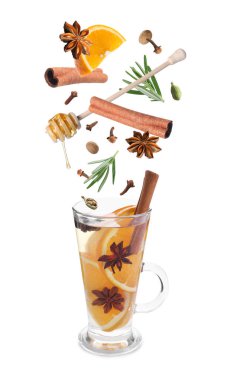 Sıcak şarap tarifi. Baharatlar ve diğer malzemeler cam bardağa dökülüyor ve beyaz arka planda içecek var.