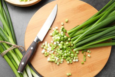 Yeşil soğan ve bıçak gri masada, düz yatıyordu.