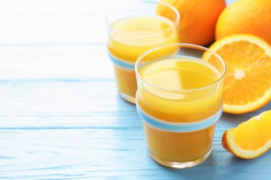 Taze portakal suyu ve açık mavi ahşap masada meyveler, yakın plan. Metin için boşluk