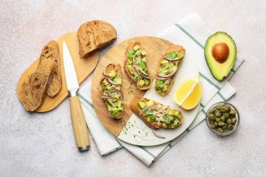 Avokado, soğan ve mikroyeşilliklerle nefis bruschetalar hafif desenli masada servis edilir.