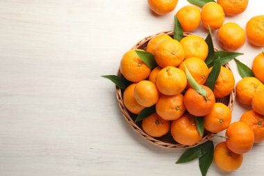 Taze mandalina ve yeşil yapraklar beyaz ahşap masada, düz yerde. Metin için boşluk