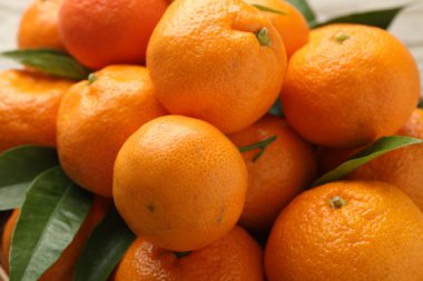 Taze mandalina ve yeşil yapraklar masada, yakın plan.