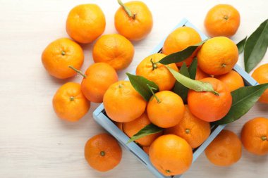 Taze mandalina ve yeşil yapraklar beyaz ahşap masada, düz yatıyordu.