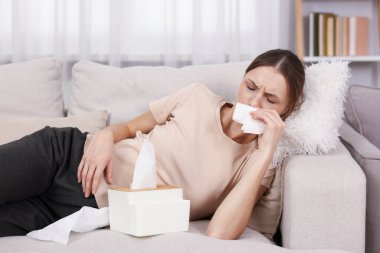 Evdeki kanepede burnu akan hamile bir kadın. Soğuk Semptom