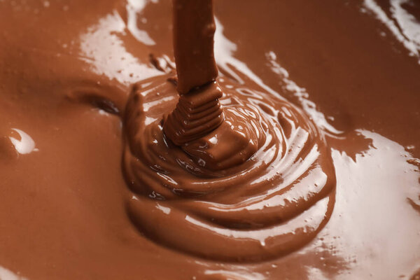 Tasty melted chocolate flowing down, closeup view