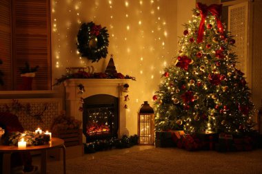 Güzel bir şömine, Noel ağacı ve karanlık odada şenlikli bir dekor. İç tasarım