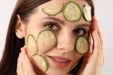 Beyaz arka planda salatalık dilimleri olan bir kadın.