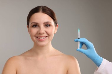 Estetik ameliyat. Doktor gri arka plandaki hastaya yüz enjeksiyonu yapıyor.