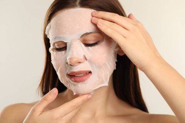 Açık gri arka planda yüz maskesi olan kadın.